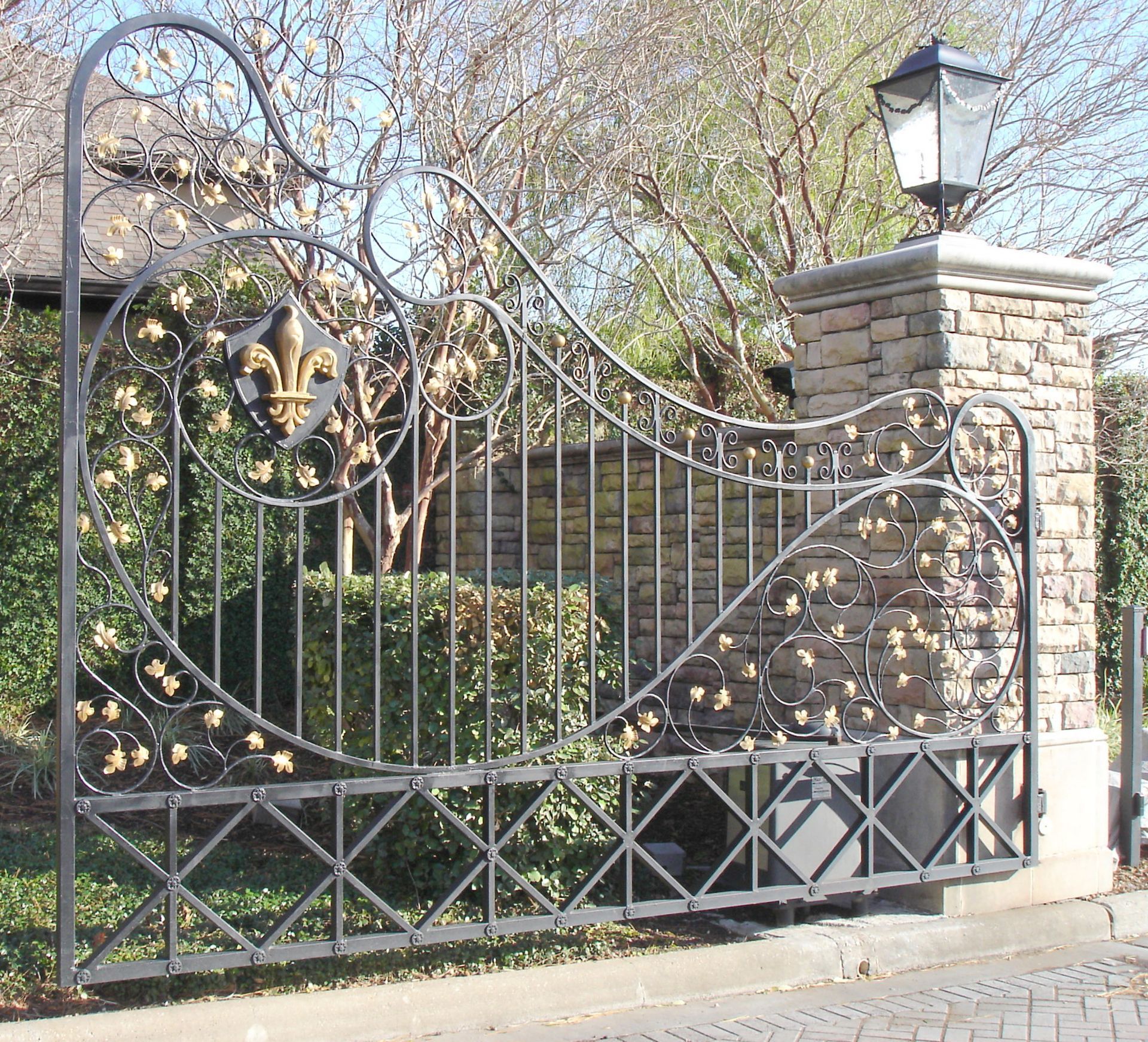 A wrought iron gate with a stone pillar in the background