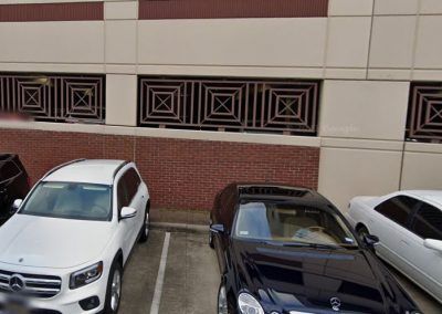 Three cars are parked in a parking lot in front of a building.