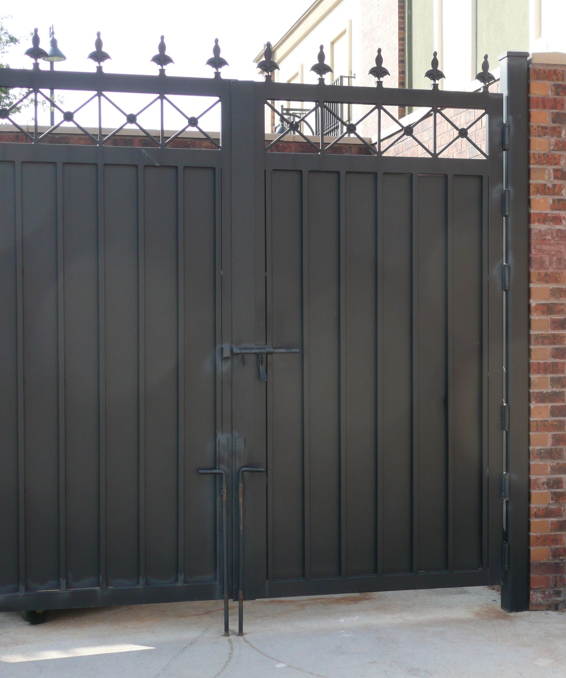 A black gate with a brick wall behind it
