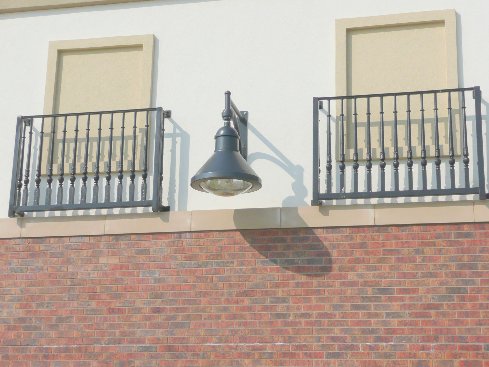 A brick wall with a balcony and a lamp on it