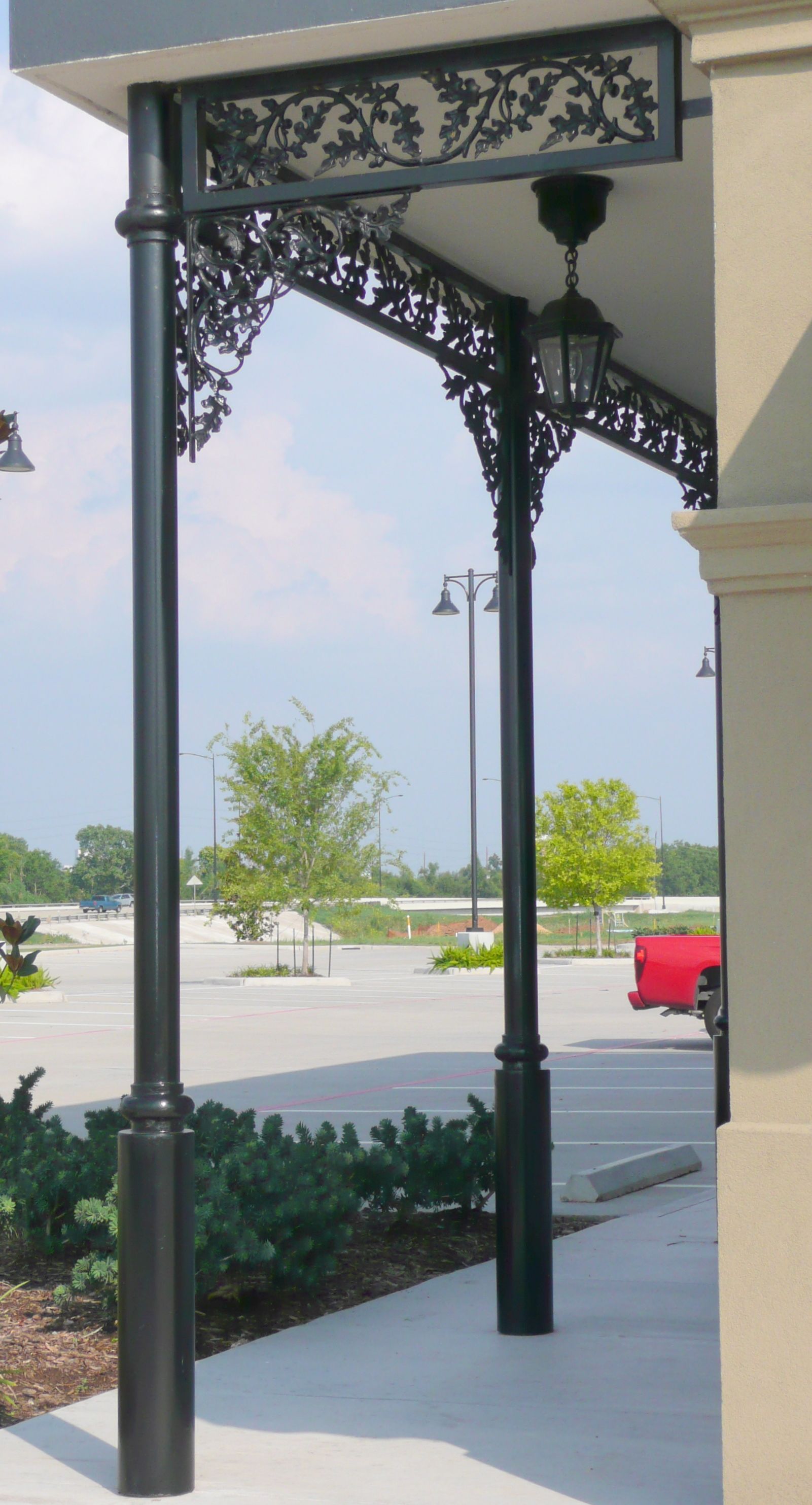 A red truck is parked in a parking lot under a canopy