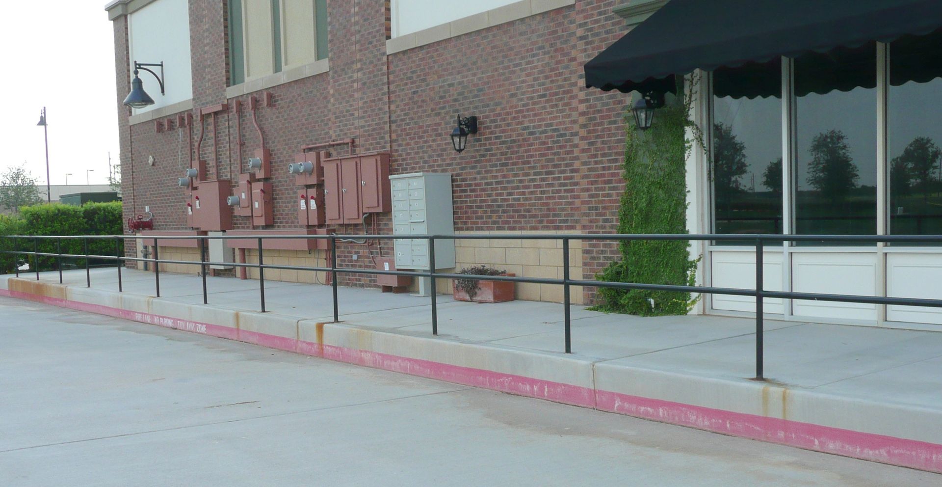 A brick building with a red curb and a black awning