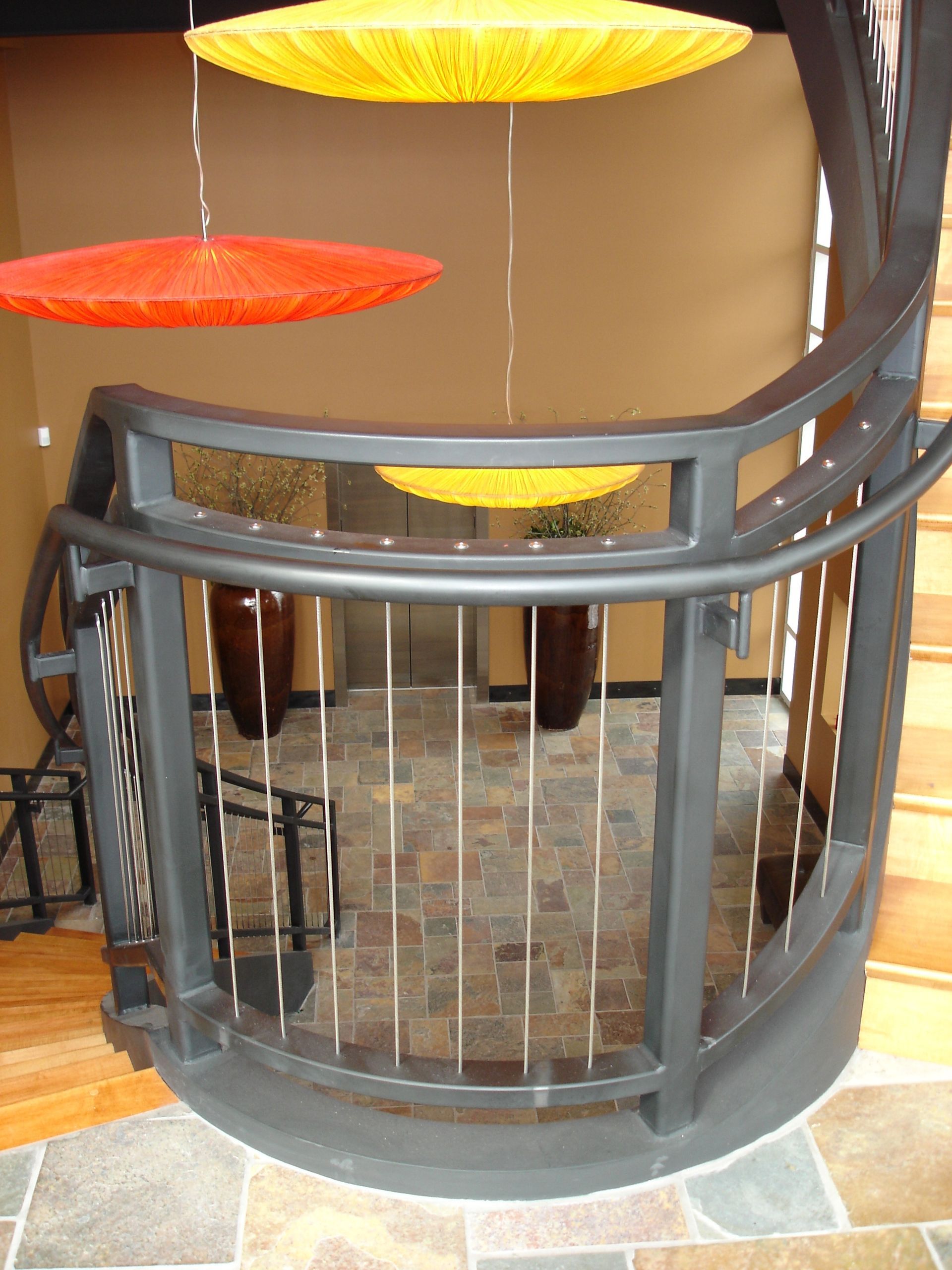 A staircase with a metal railing and umbrellas hanging from it