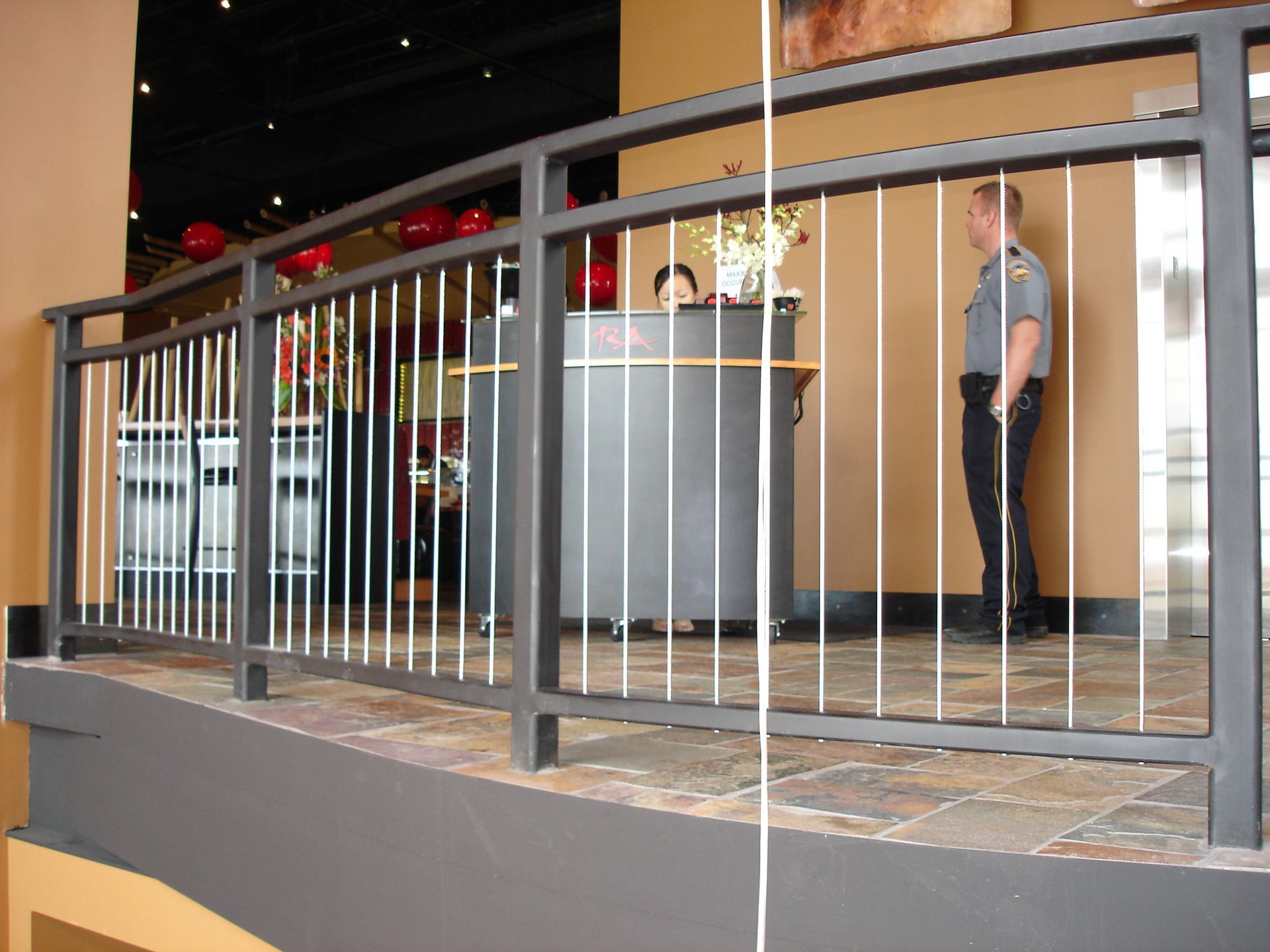 A man standing behind a metal railing in front of a counter