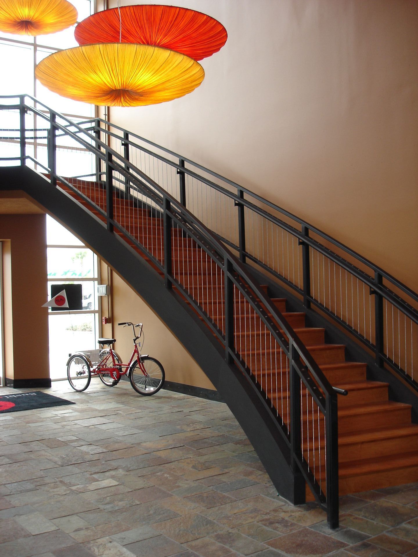 A red bicycle is parked under a staircase in a building