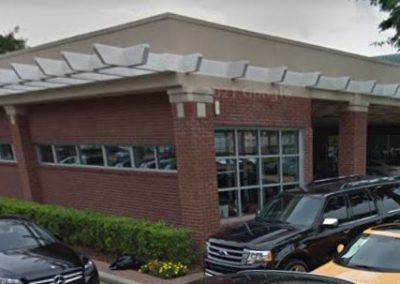 A row of cars are parked in front of a brick building.
