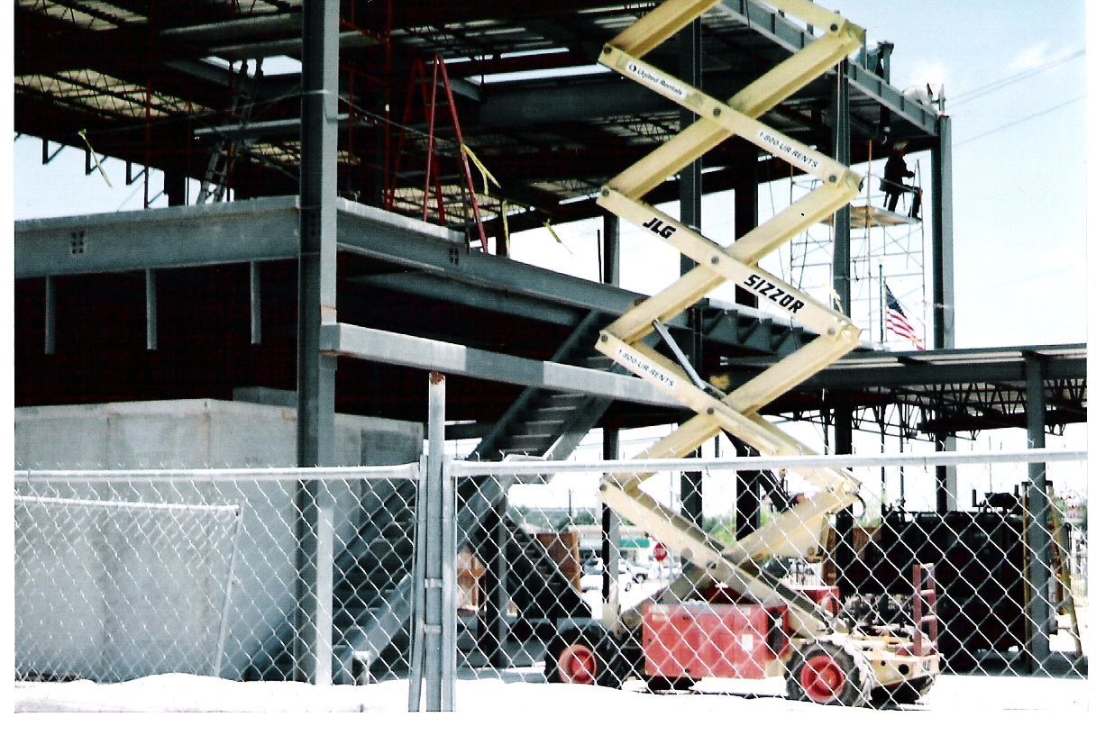 A construction site with a chain link fence and a scissor lift