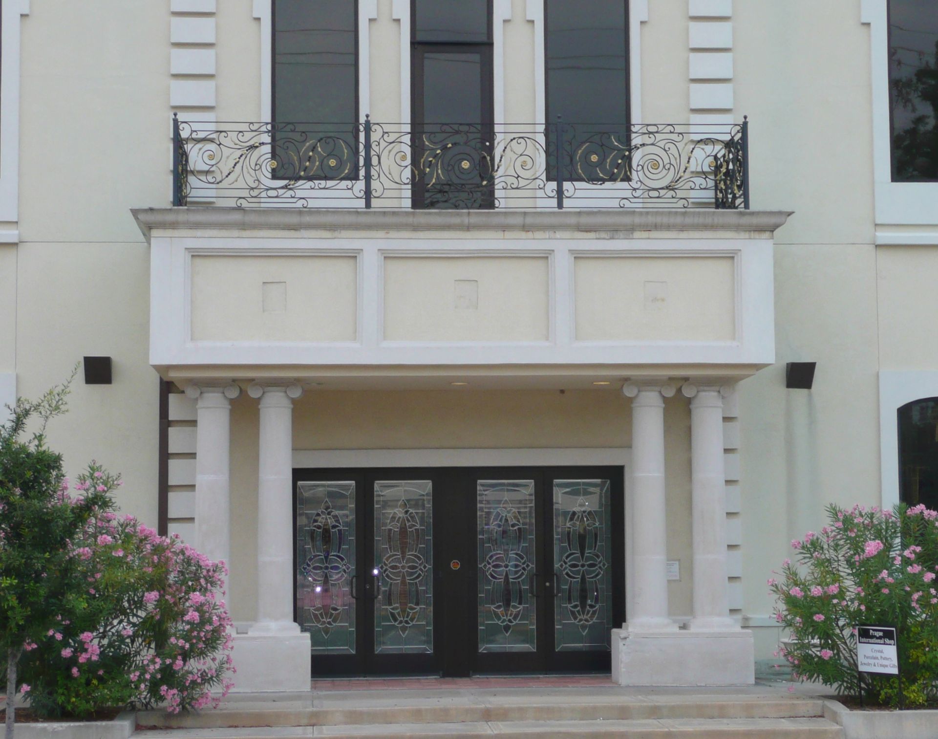 A large white building with a balcony and flowers in front of it