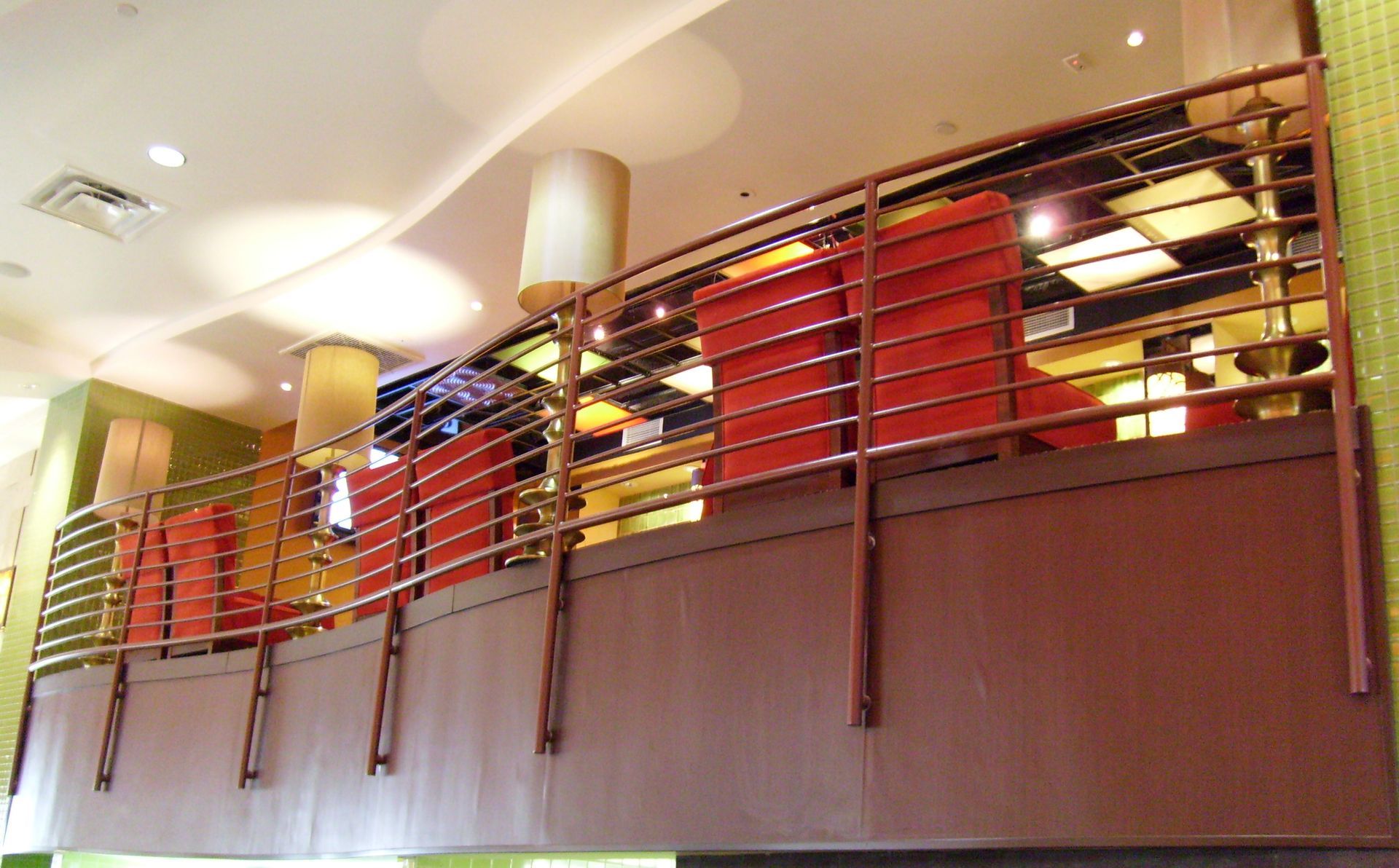 A balcony in a restaurant with red chairs and lamps