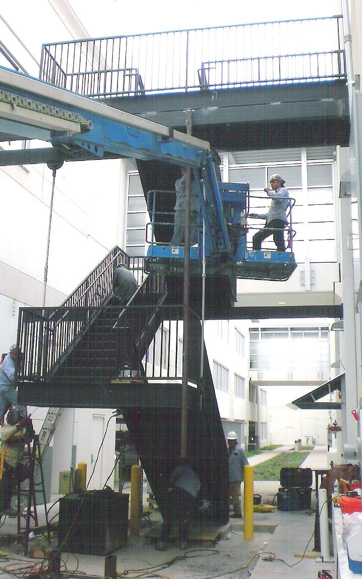 A man is standing on a crane over a set of stairs