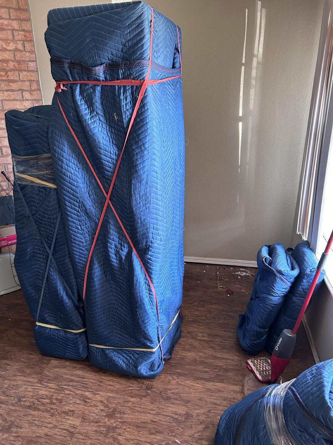 White glove Wrapped antique furniture ready for moving; blue padding secured with red moving bands.