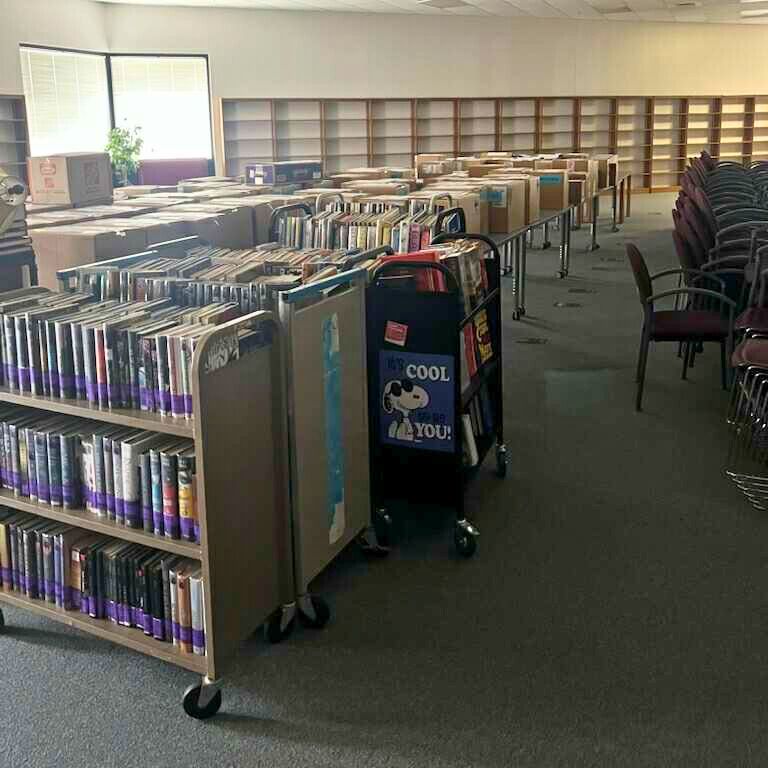 Library with bookshelves, many book carts, and rows of empty bookshelves.