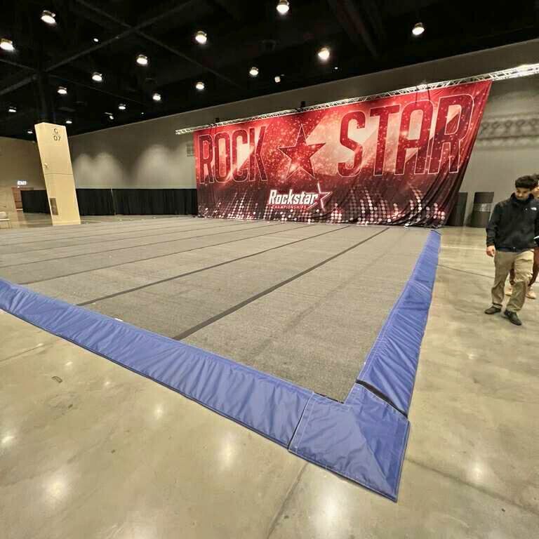 Large, empty gymnasium with a cheerleading mat and a