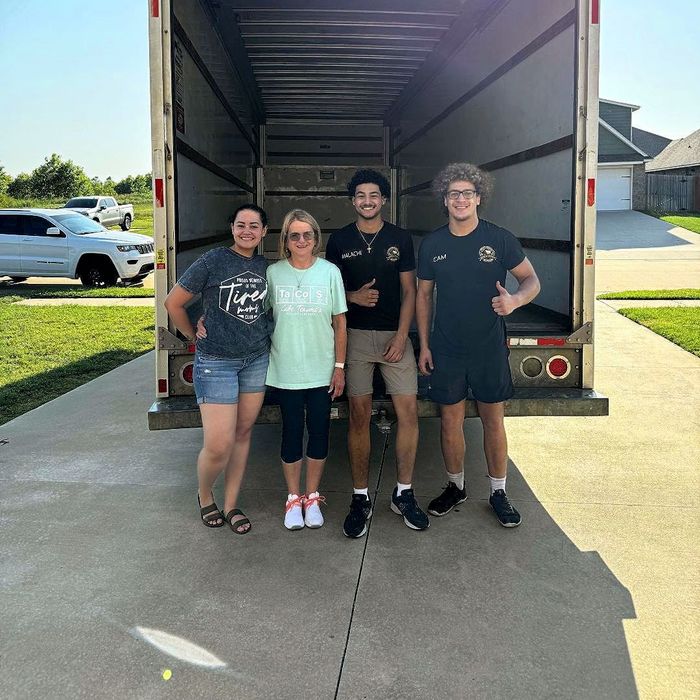 A group of people are standing in front of a moving truck.