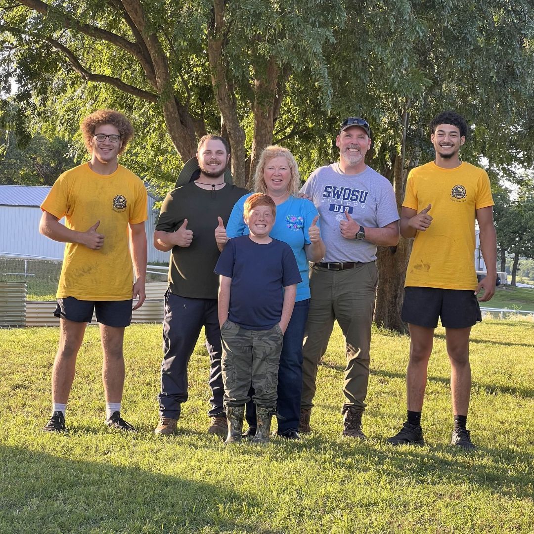 A group of people are posing for a picture in a grassy field.