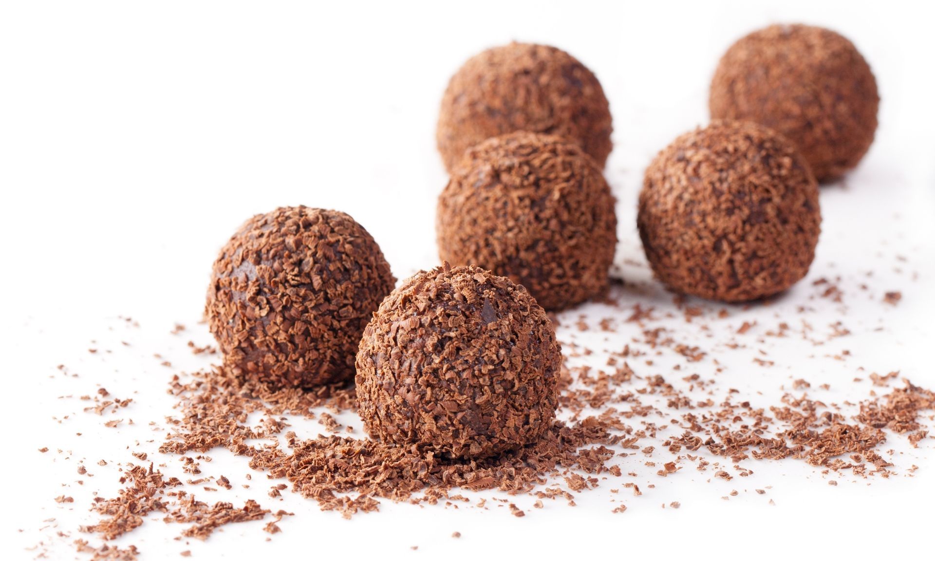 Een groep chocoladetruffels bedekt met chocoladepoeder op een wit oppervlak.