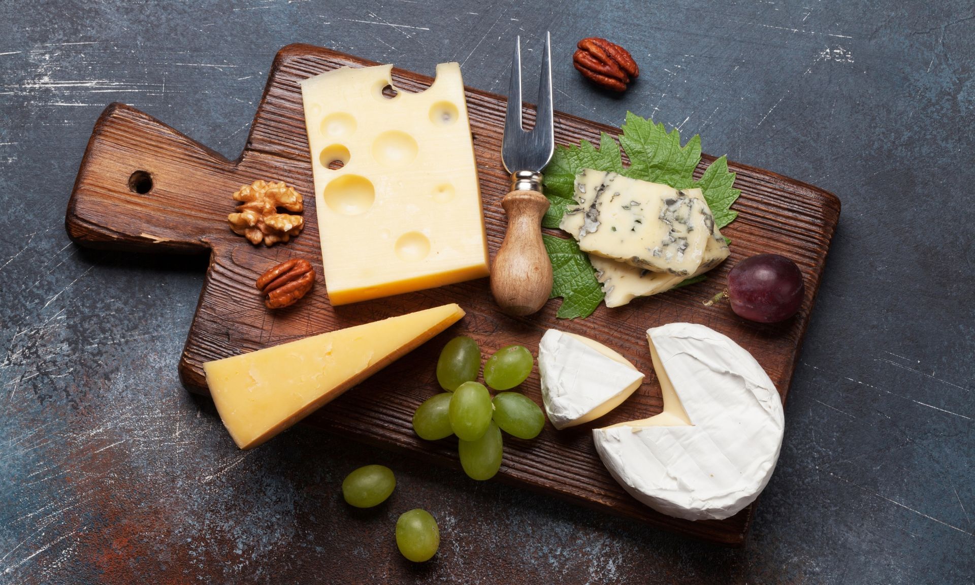 Er liggen veel verschillende soorten kaas op de snijplank.