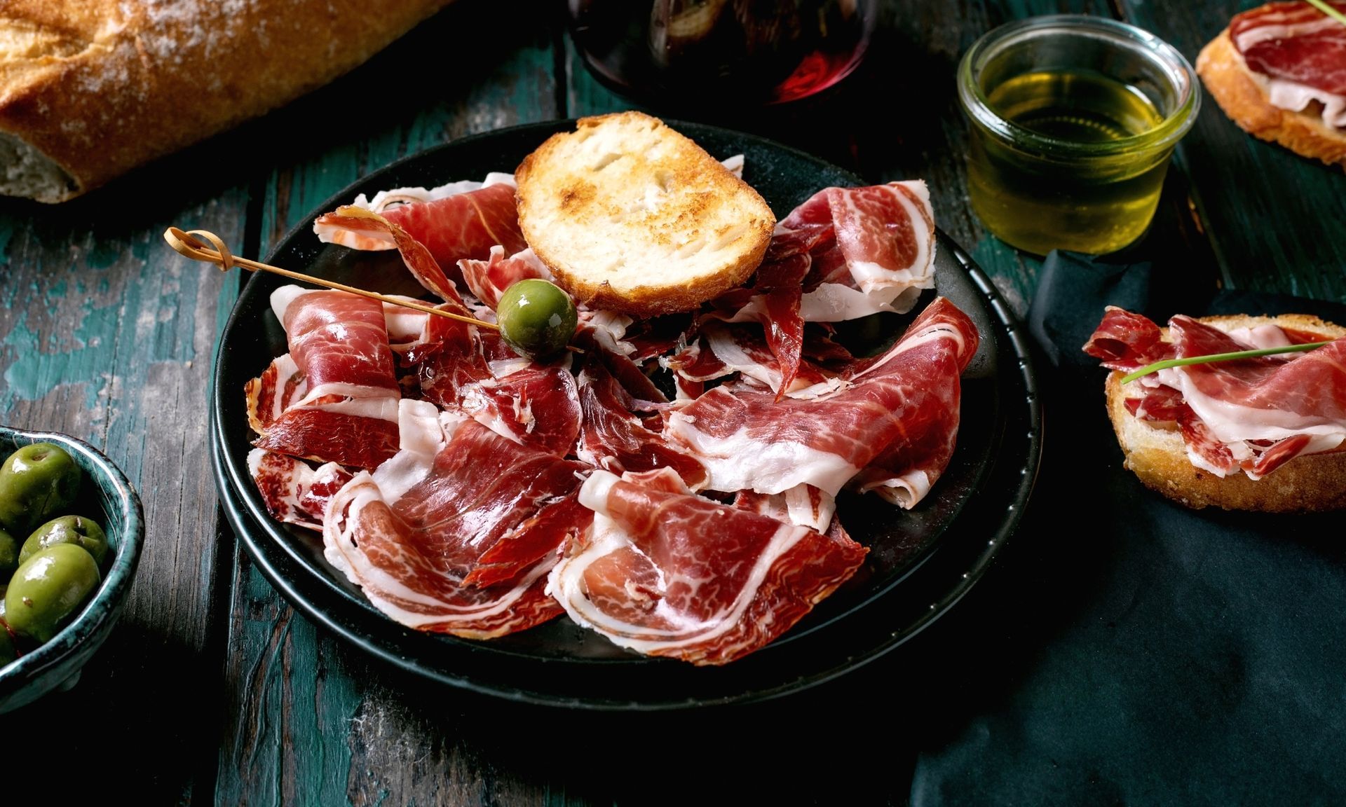 Een bord met vlees en brood op een houten tafel.