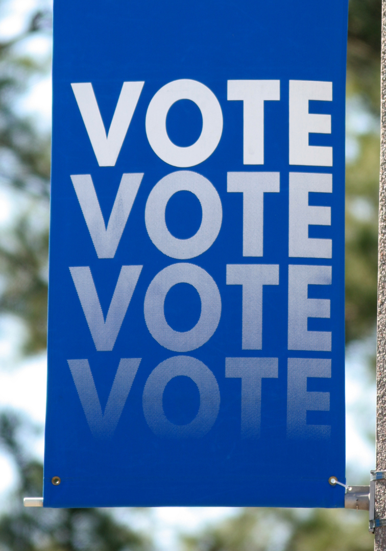 A blue sign that says vote vote vote vote