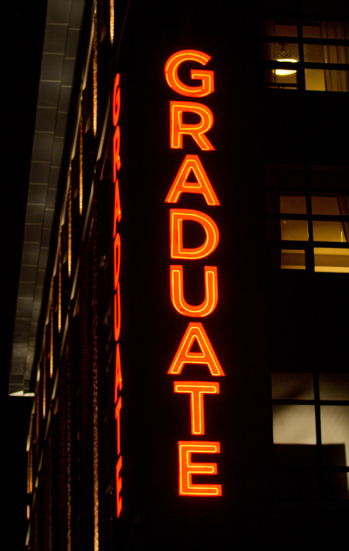 A neon sign on the side of a building that says graduate