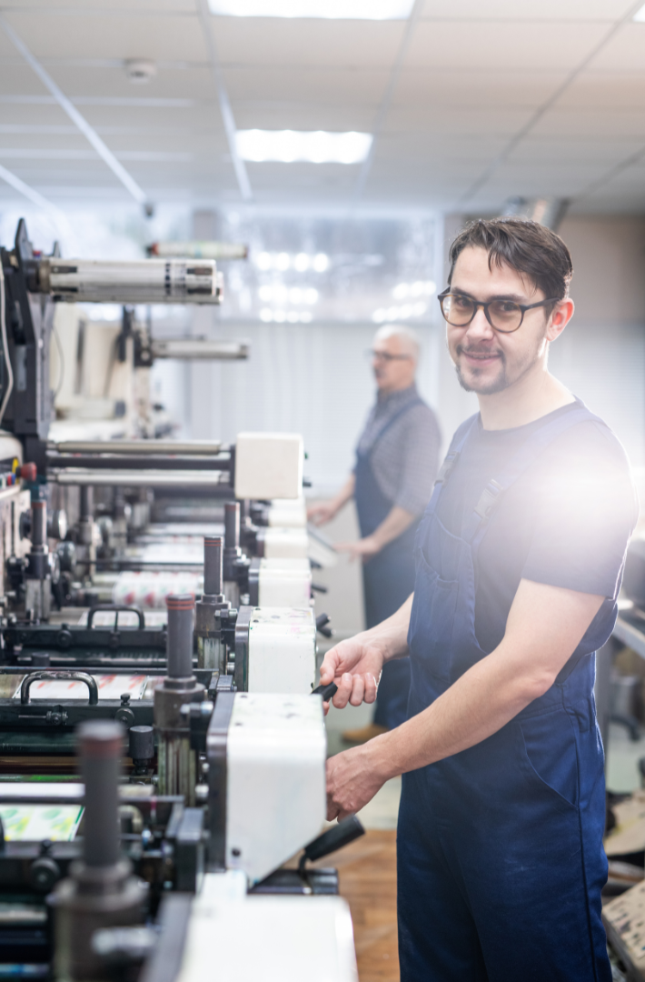 A man is standing in front of a machine in a factory.