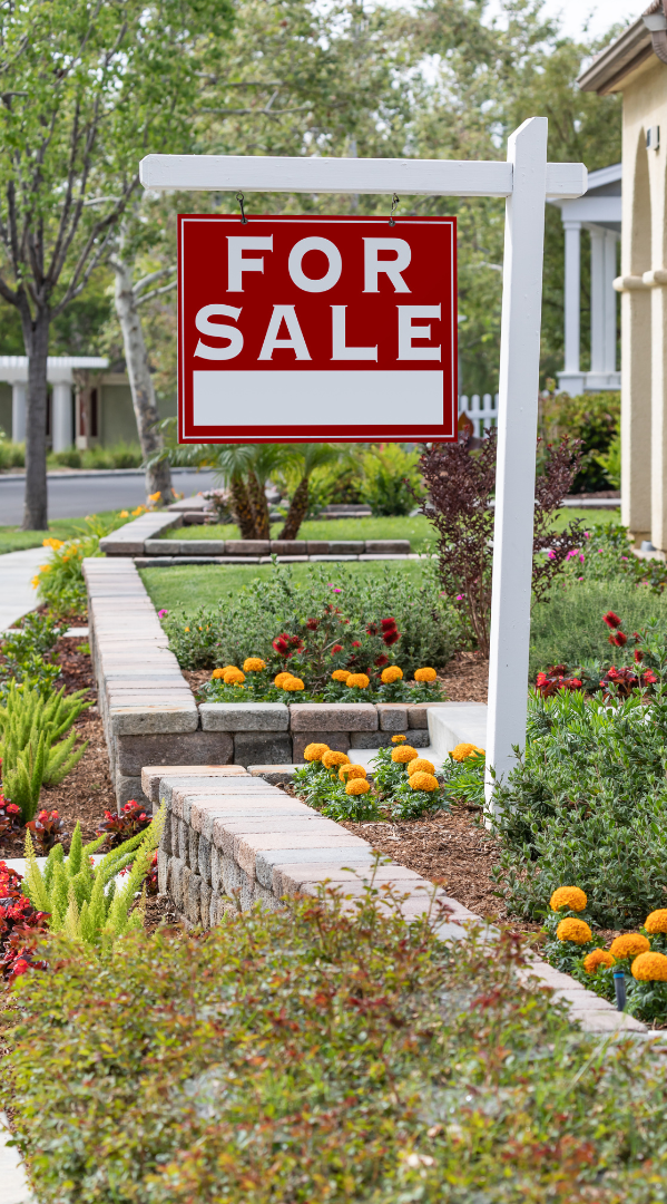 A for sale sign is in the front yard of a house.