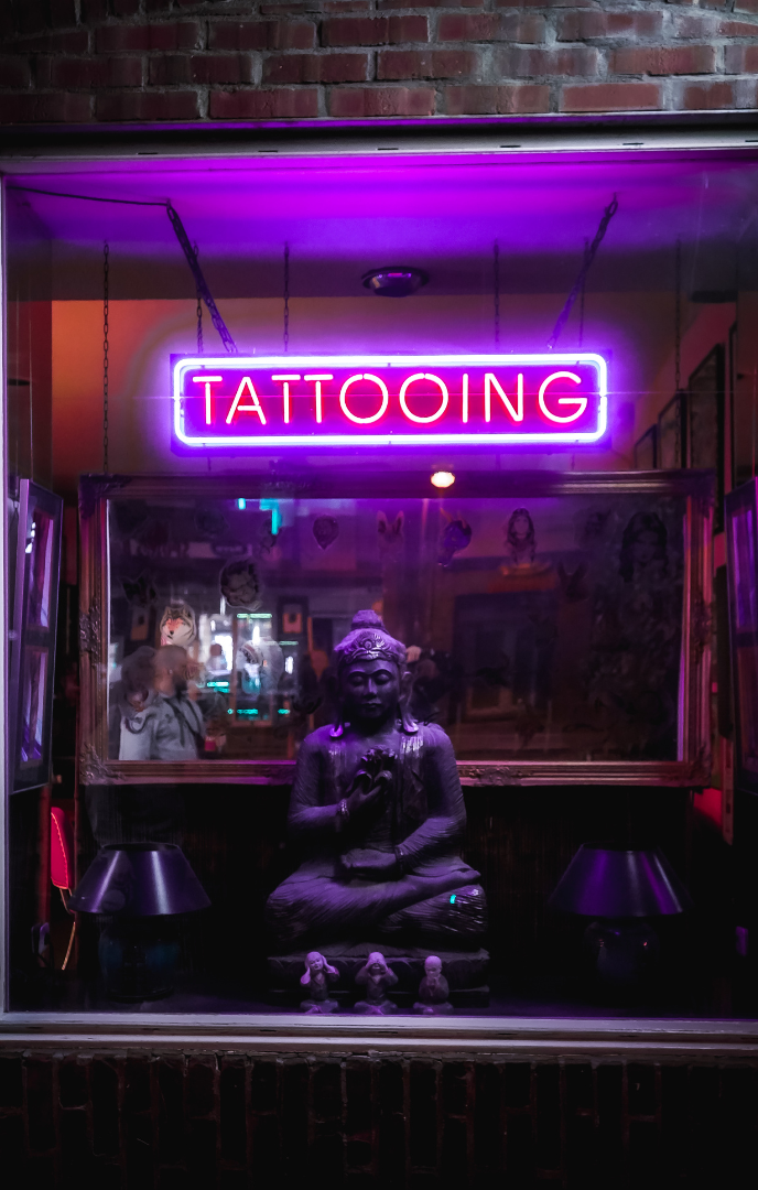 a neon sign that says tattooing on a window of a shop