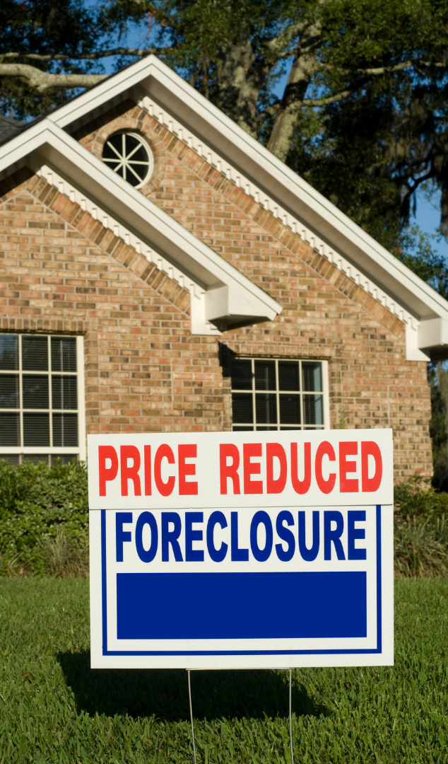 A house with a price reduced foreclosure sign in front of it