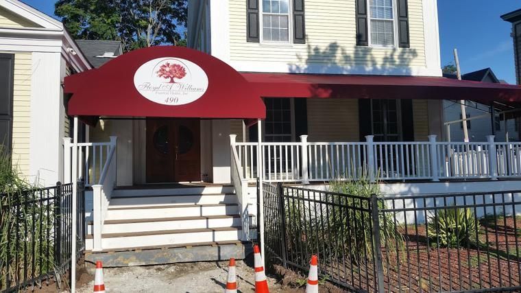 A white house with a red awning over the entrance
