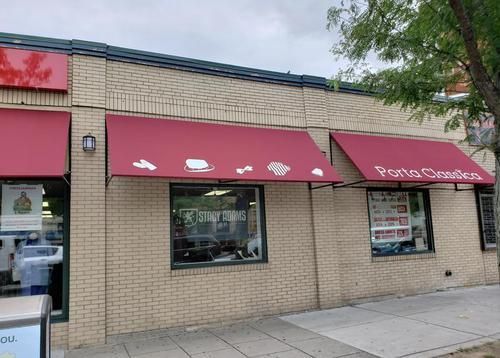 A brick building with two red awnings on the side of it.