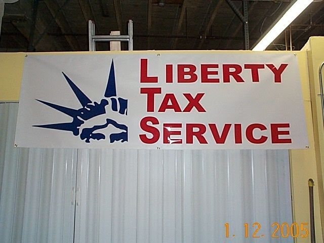 A sign for liberty tax service hangs on a wall