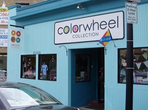 A car is parked in front of a store called colorwheel collection