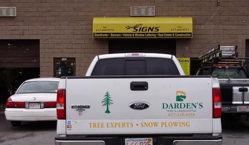 A white truck is parked in front of a building that says darden 's tree experts snow plowing