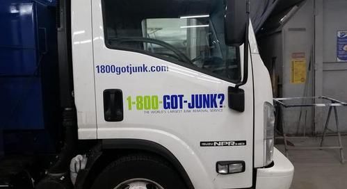 A white garbage truck is parked in a garage.