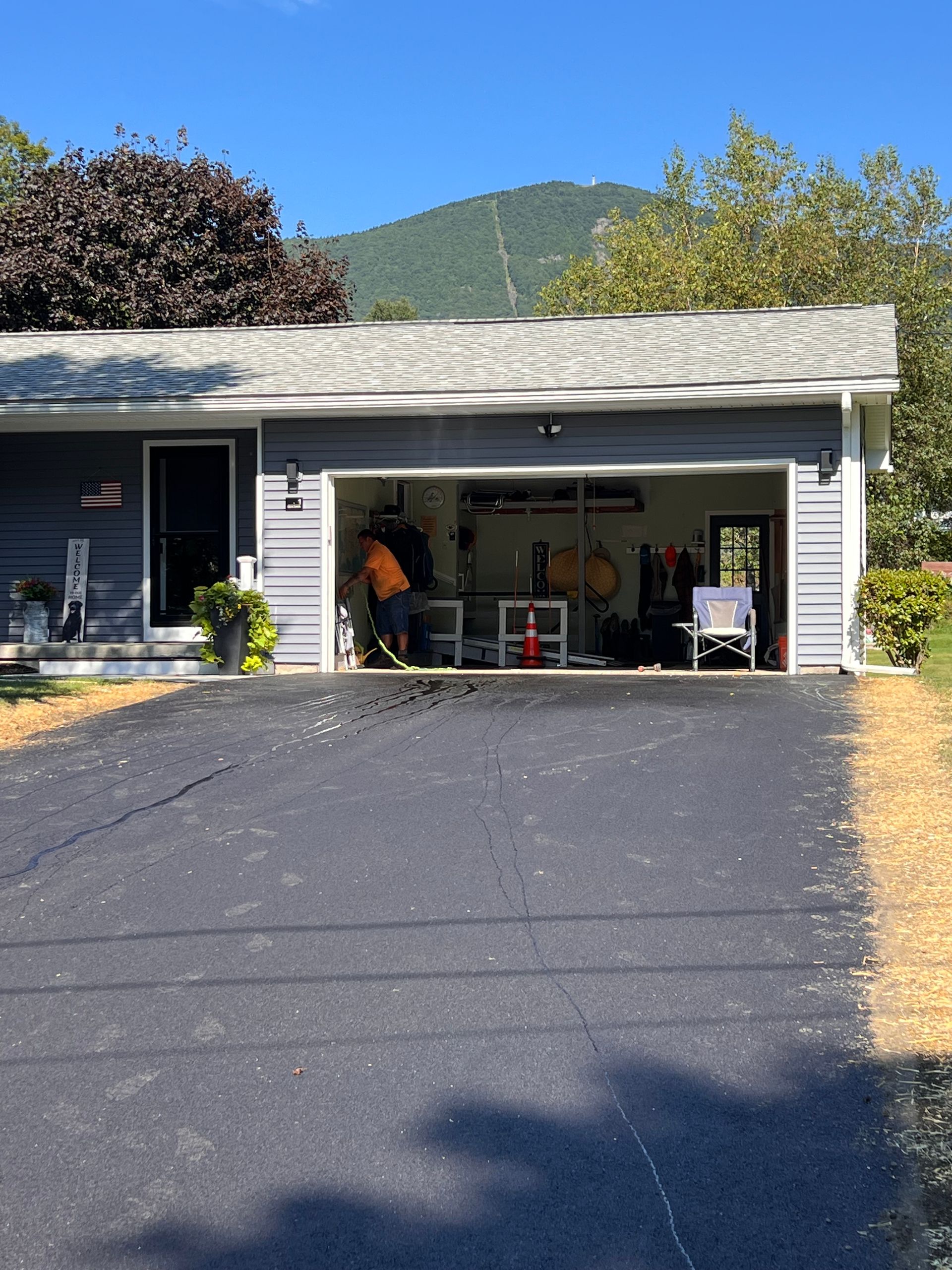 A garage with an open door, a person inside, and a mountain in the background.