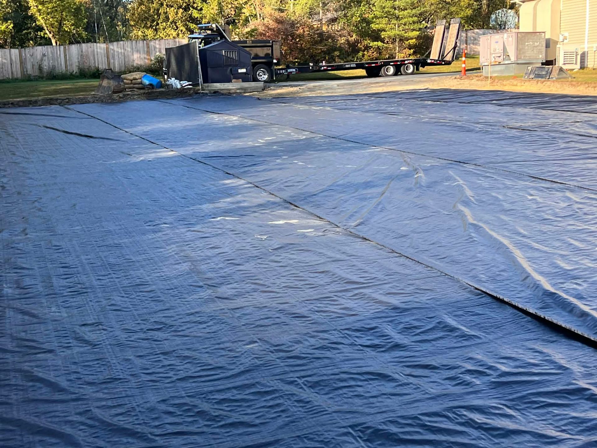 Dark blue pool cover on a backyard, some wrinkles visible.