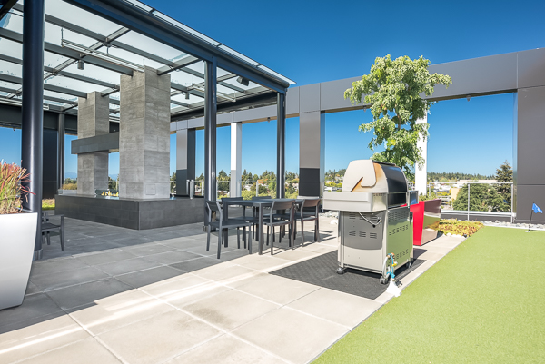 Photo of a rooftop lounge area with a barbecue grill and shaded area