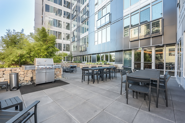 Photo of a community outdoor lounge area, with a barbecue grill in sight