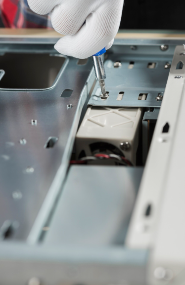 Una mano enguantada utiliza un destornillador para asegurar un componente dentro de la carcasa de una computadora.