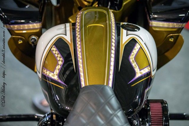 Een close-up van een motorfiets met een paarse en gouden lak.