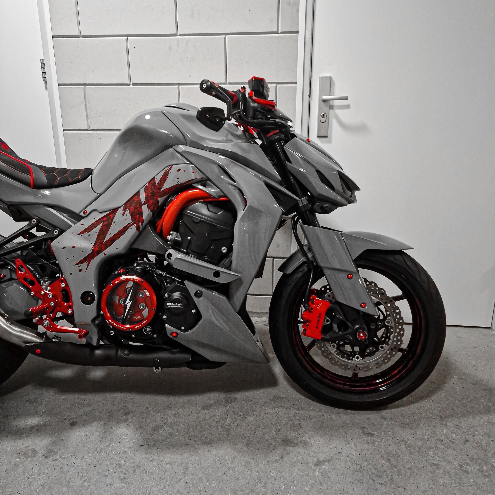 Een grijze en rode Kawasaki motorfiets staat geparkeerd in een garage