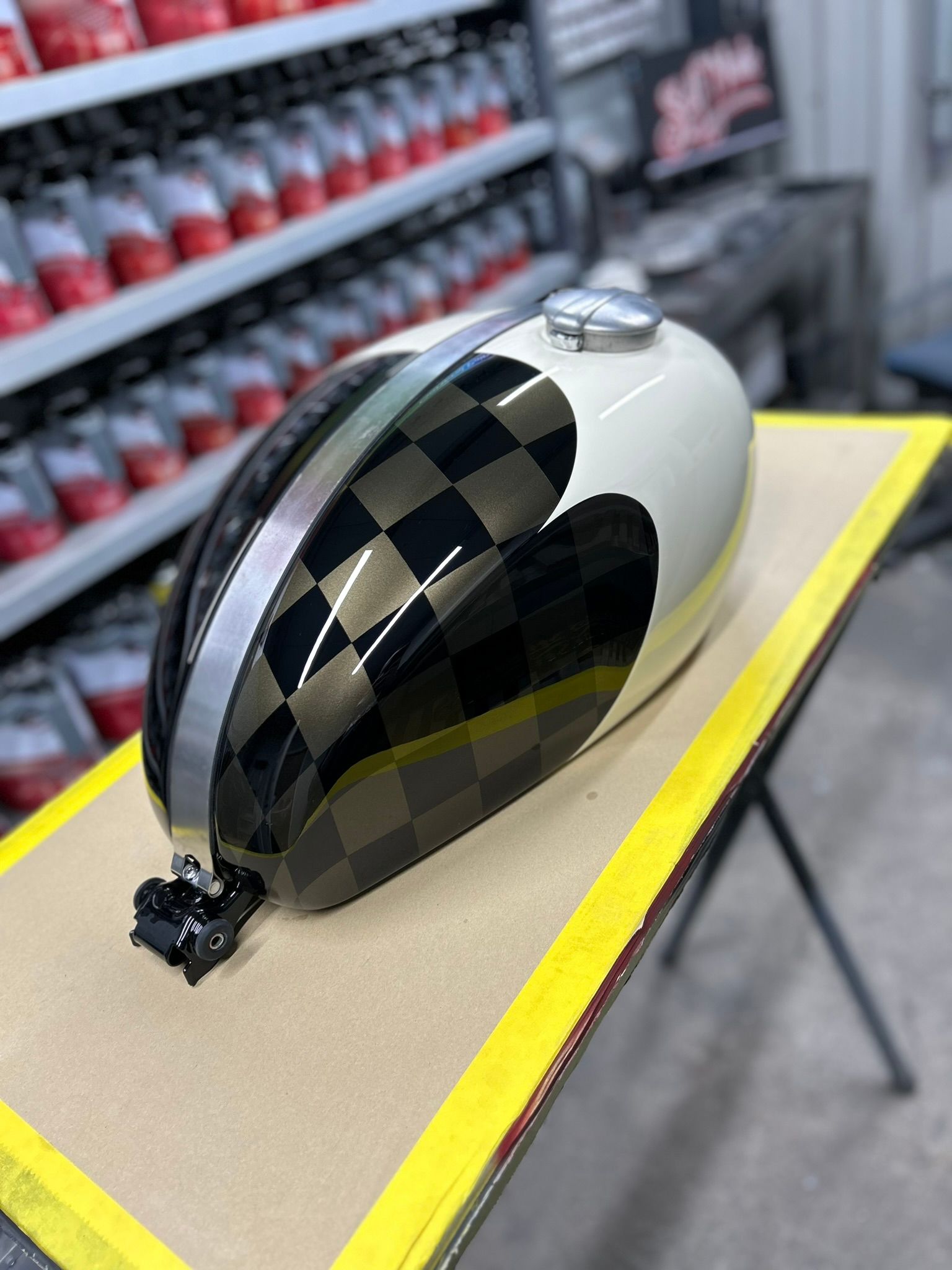 Een benzinetank van een motorfiets staat op een houten tafel.