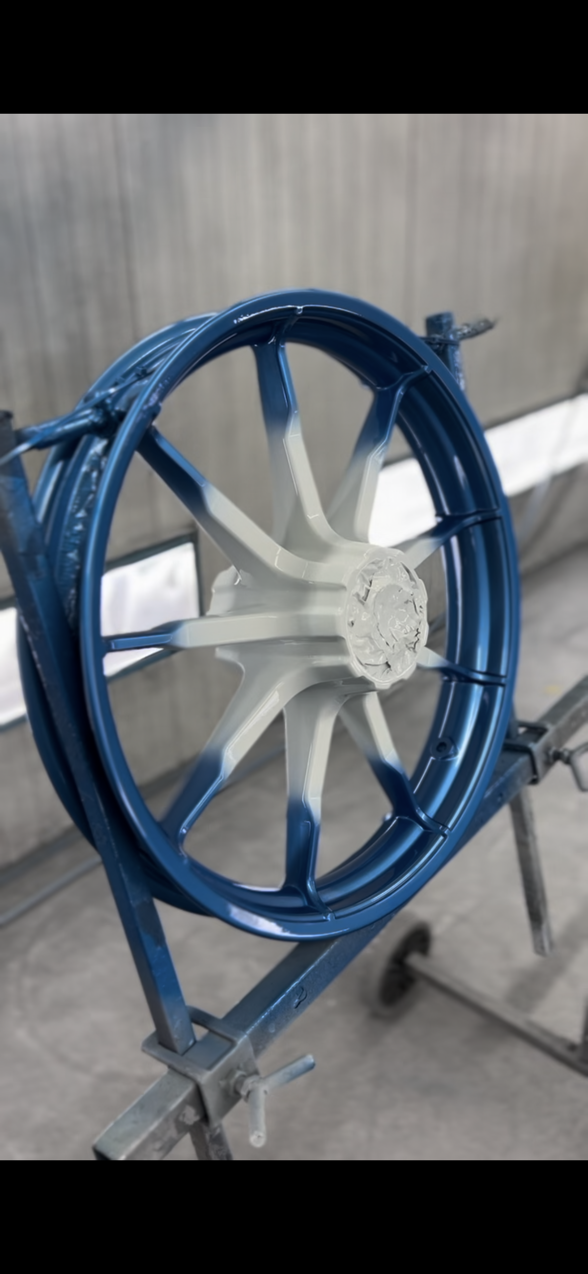 Een blauw en wit wiel staat op een metalen standaard.