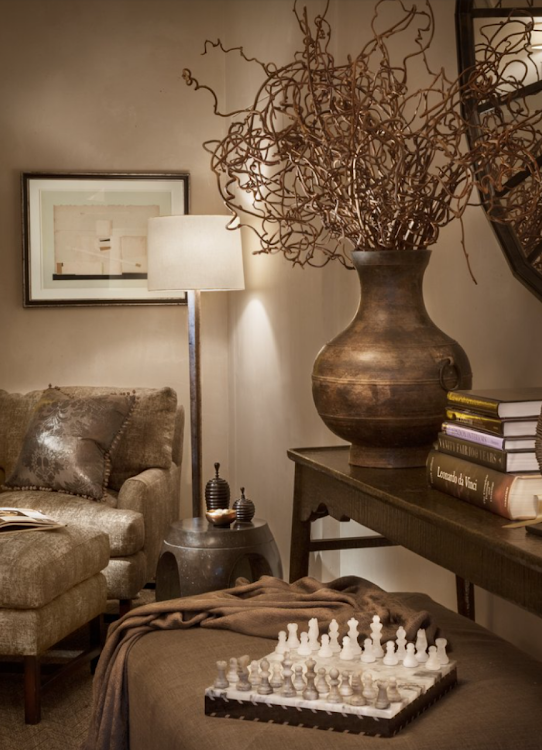Cozy living room with leather chair, floor lamp, bronze vase, and chess set on a table