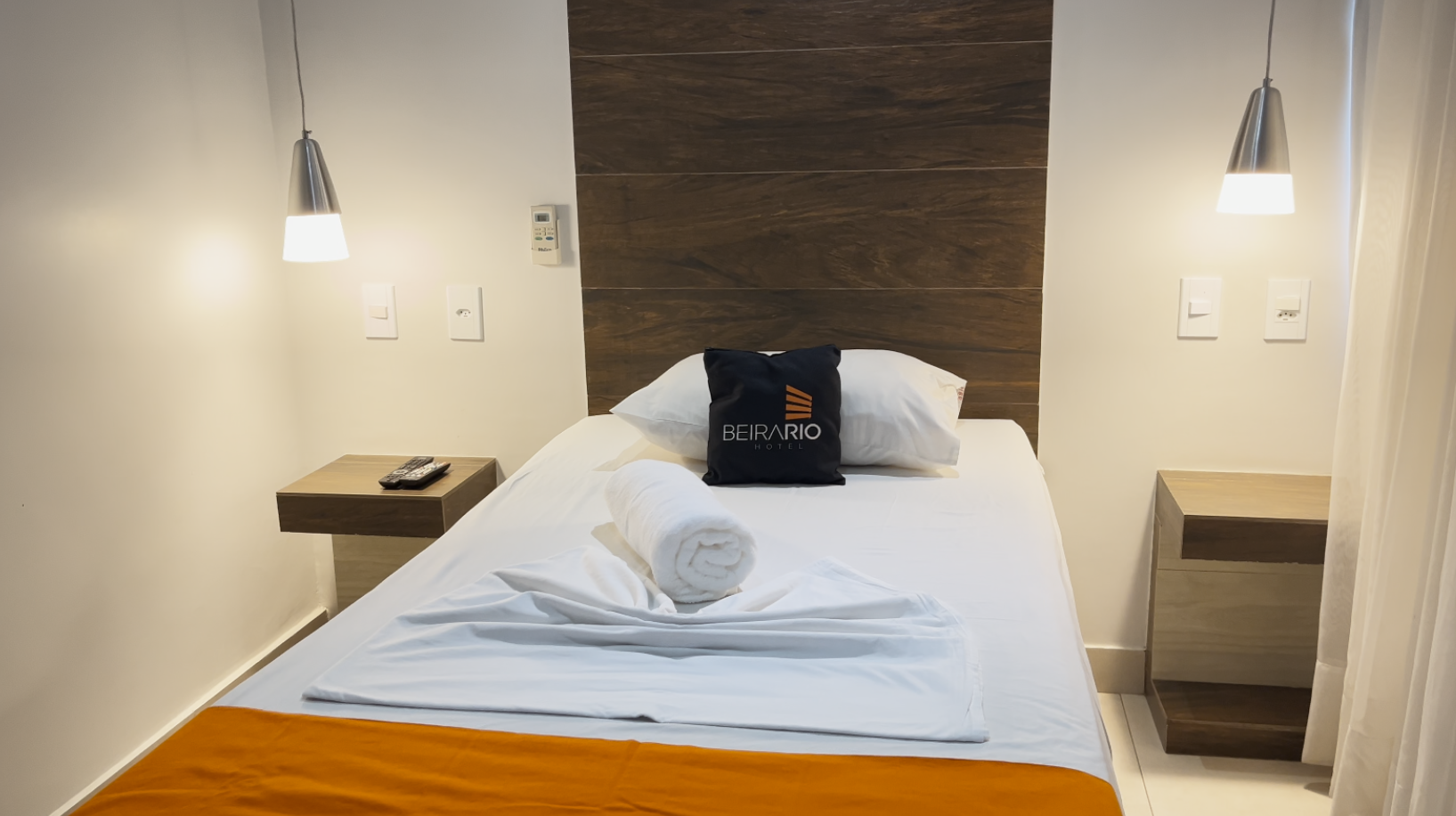 Um quarto de hotel com uma cama de solteiro e duas mesas de cabeceira