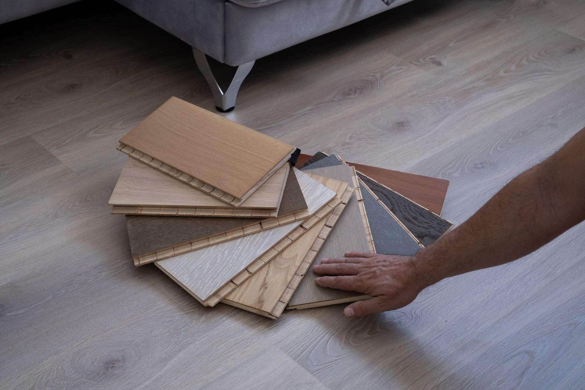 A person is holding a swatch of wooden flooring.