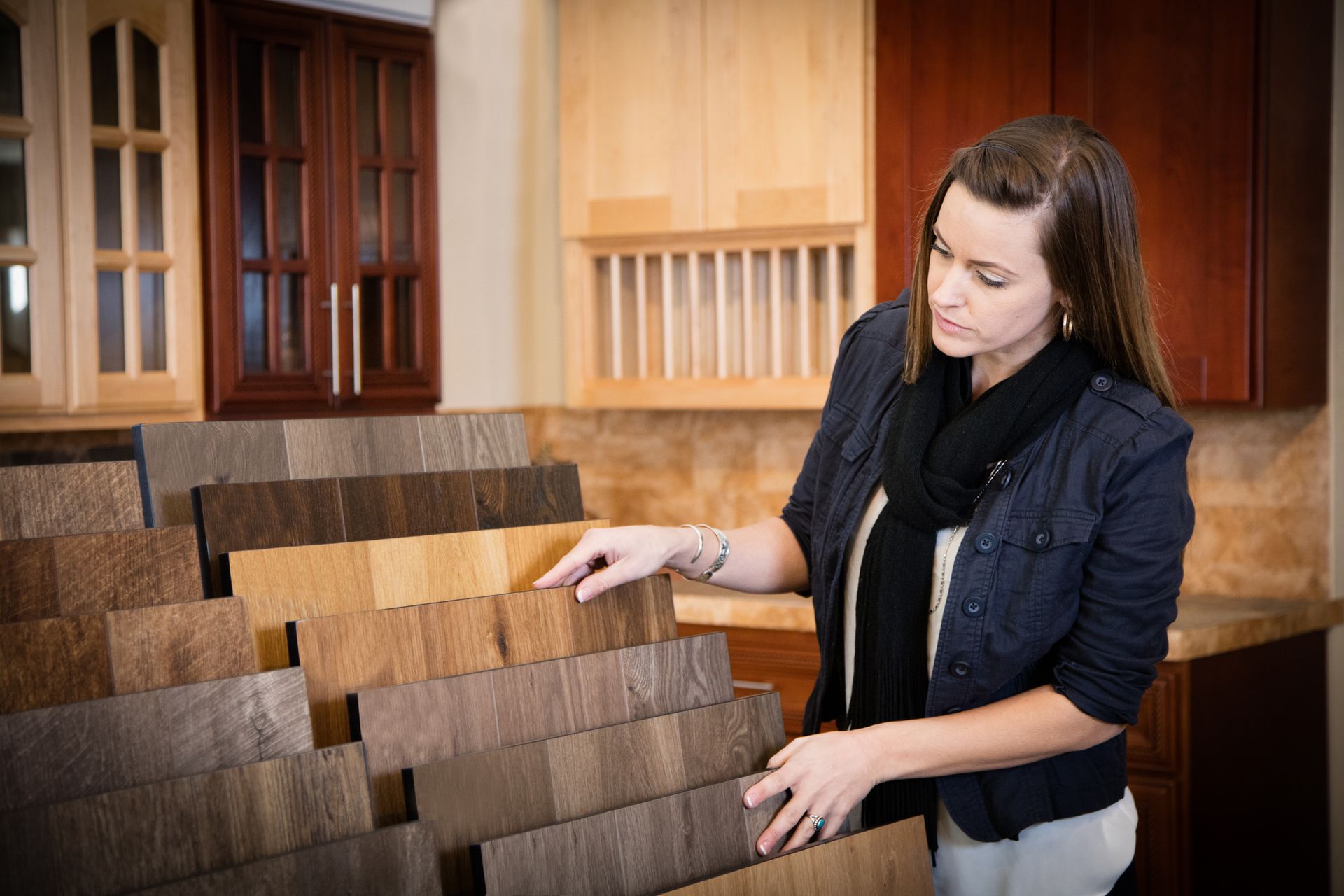 A woman is looking at samples of wood in a kitchen showroom.