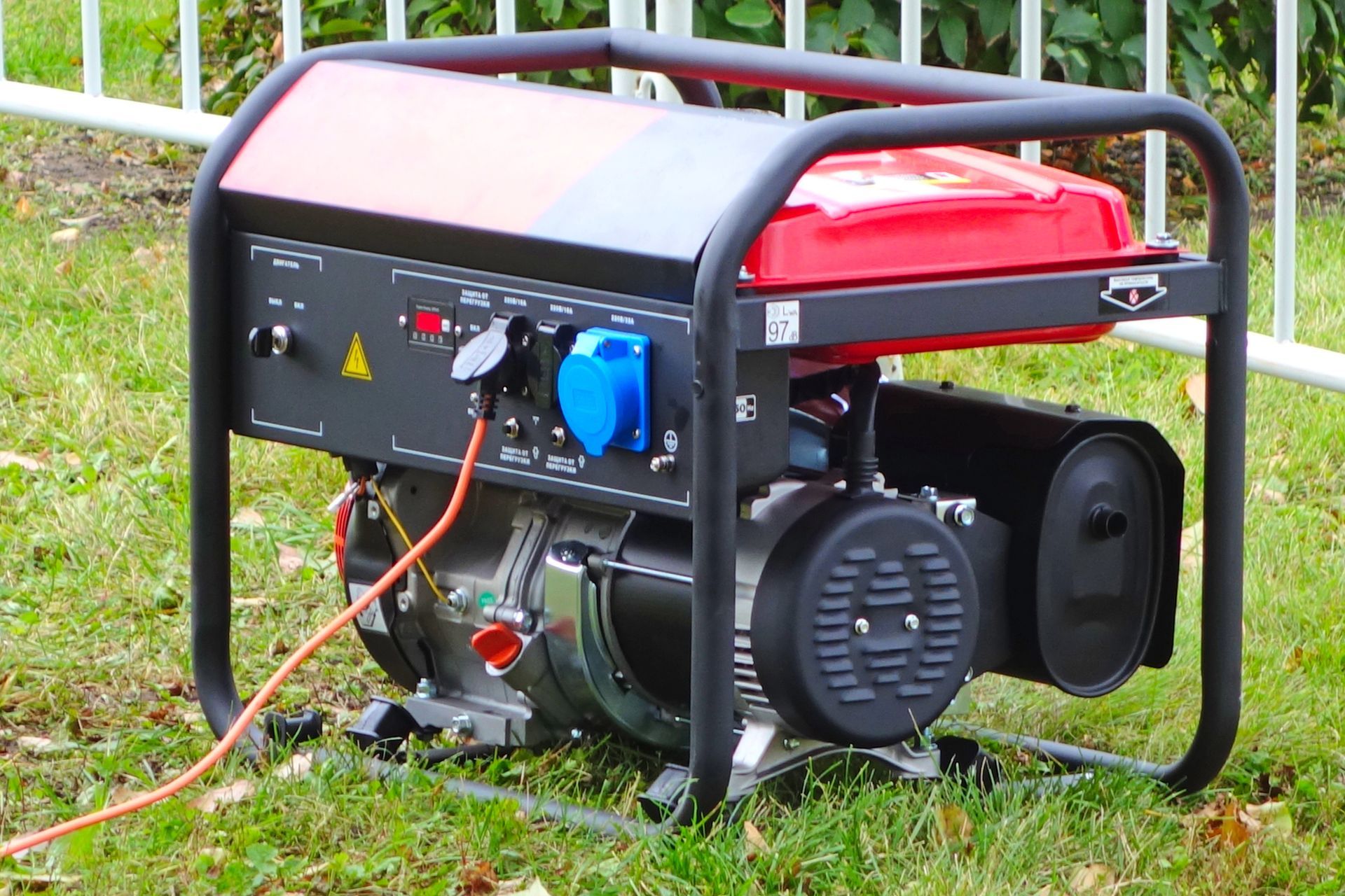 A red and black generator is sitting on top of a lush green field.