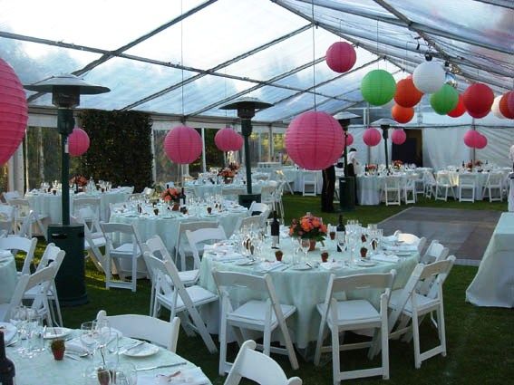 Tables and chairs are set up under a clear tent for a wedding reception