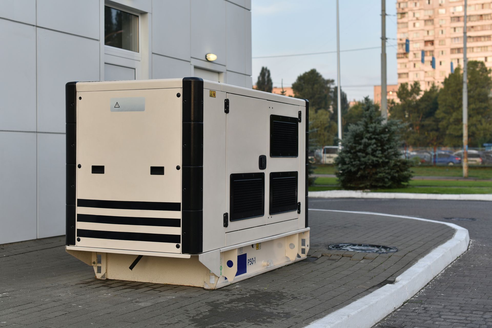 A large white and black generator is parked in front of a building.